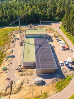 Bird's eye view of a construction site with solar panels and surrounded by forest, visible with