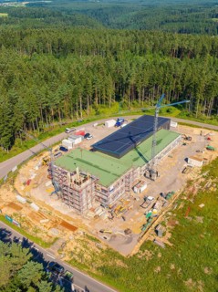 A building with solar panels and a crane in a wooded industrial area, new fire station building,