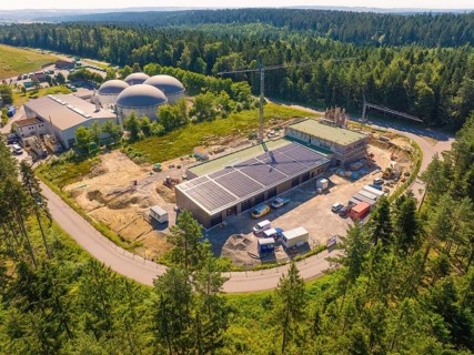 Embedded in a forest landscape, the picture shows solar systems on buildings at a construction
