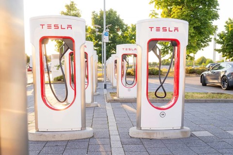 Tesla charging stations in a sunny environment with green trees in the background, Tesla