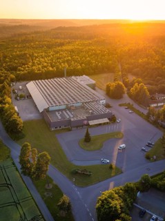 Factory building from the air at sunset, surrounded by woods and roads, Schnaufer sparkling wine