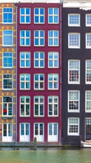 Holland, Amsterdam Damrak canal houses with scenic bridges in historic center, UNESCO Heritage site