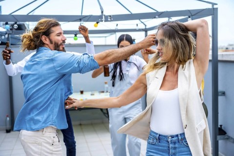 Cheerful young people dancing and having fun at a rooftop party, celebrating friendship and