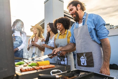 Chefs grilling colorful vegetables and sausages while friends enjoy drinks and laughter at a lively
