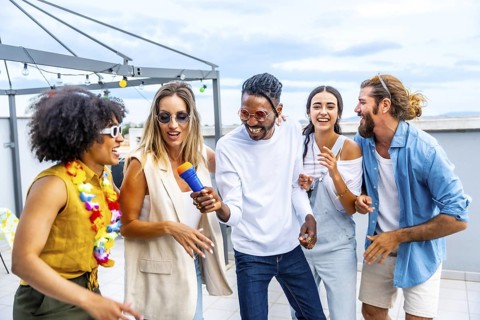 Diverse group of friends enjoying a lively karaoke session, singing, dancing, and celebrating