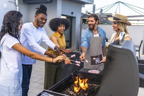 Happy friends enjoying a rooftop barbecue, roasting marshmallows over glowing flames while sharing