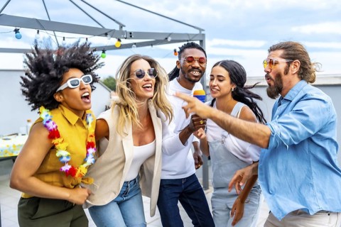 Cheerful multi ethnic friends enjoying a vibrant rooftop party, singing karaoke, dancing, and