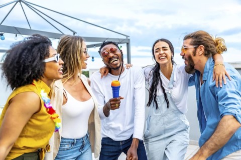 Five cheerful friends singing karaoke and enjoying a lively rooftop party, creating unforgettable