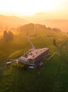 Large building on a hill at sunset in a peaceful mountain landscape, Alpe di Siusi, Dolomites,