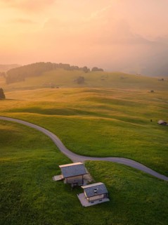 Houses and streets in a hilly landscape in warm evening light, Alpe di Siusi, Dolomites, South