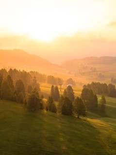 Dreamy sunrise mood with forests and mountains in the distance, Alpe di Siusi, Dolomites, South