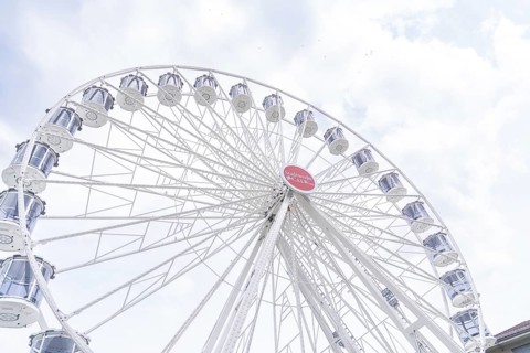 Modern Ferris wheel with gondolas in front of a slightly cloudy sky, Ferris wheel construction,