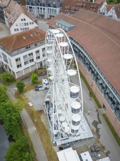 Close-up of a white Ferris wheel in an urban area with several buildings and a river, Ferris wheel