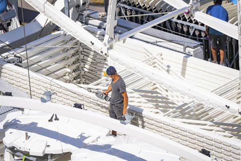 Person standing between technical structures while a Ferris wheel is being erected, Ferris wheel