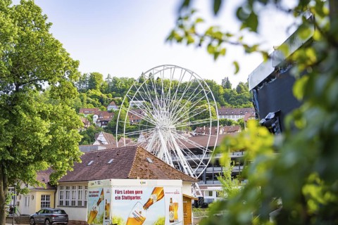 Ferris wheel behind buildings and trees in a summer setting, Ferris wheel construction for the