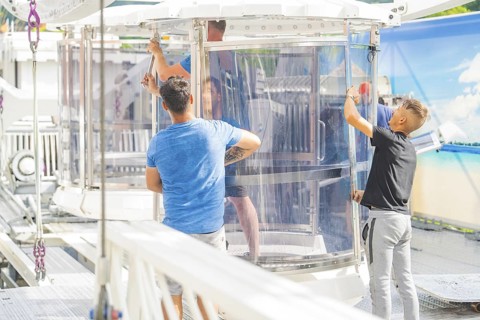 People working on a glass cabin of a Ferris wheel in an amusement park, Ferris wheel construction