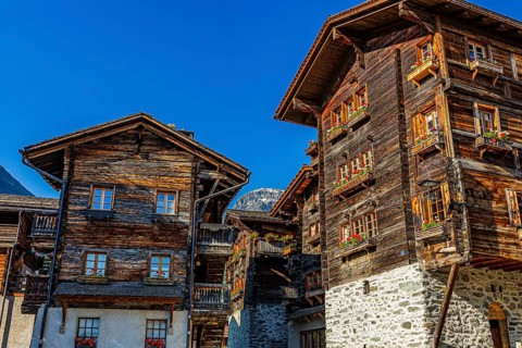 Old wooden houses in log construction, decorated with flowers, historic village centre, Grimentz,