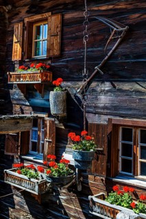 Old wooden house in log construction, decorated with flowers, historic village centre, Grimentz,