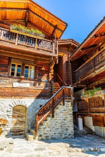 Old wooden houses in log construction, decorated with flowers, historic village centre, Grimentz,