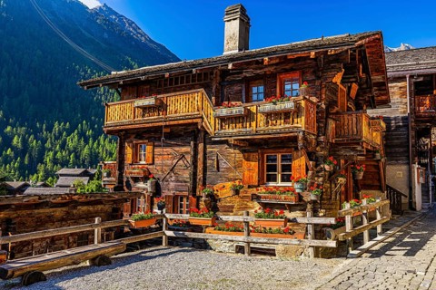 Old wooden house in log construction, decorated with flowers, historic village centre, Grimentz,