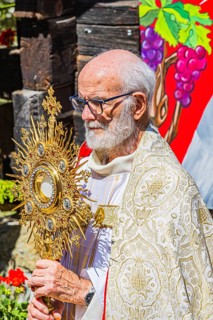 The priest with the golden monstrance during the Corpus Christi procession, historic village