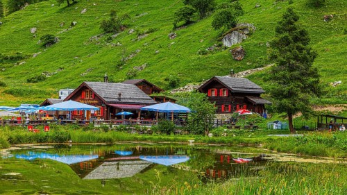 Huts and parasols reflected in the pond, Relais Tzoucdana, Zinal, Val d'Anniviers, Valais Alps,
