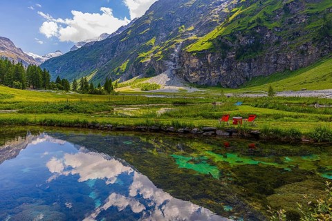 Mountains and clouds reflected in a pond, near Relais Tzoucdana, Zinal, Val d'Anniviers, Valais