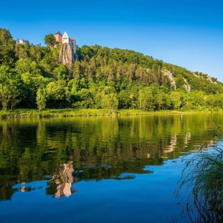 Prunn Castle on a steep cliff above the Altmühl Valley in the evening light, reflection in the