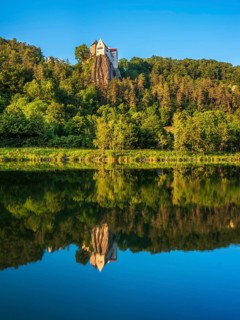 Prunn Castle on a steep cliff above the Altmühl Valley in the evening light, reflection in the