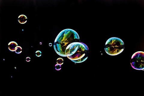 Iridescent soap bubbles in the colours of the rainbow against a black background, Recklinghausen,