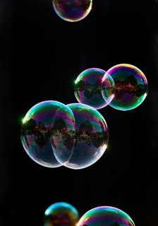 Iridescent soap bubbles in the colours of the rainbow against a black background, Recklinghausen,