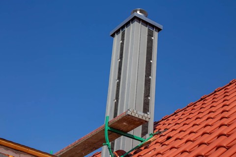 Chimney with high-quality titanium zinc cladding on a straight tiled roof
