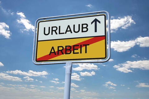 (photomontage) : Town exit sign with the inscription HOLIDAY / WORK in front of a blue sky