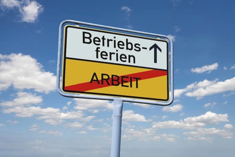 (photomontage) : Town exit sign with the inscription BETRIEBSFERIEN / ARBEIT against a blue sky