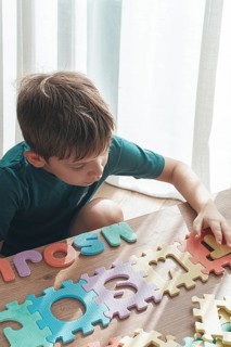 Child assembling colorful puzzle pieces on a wooden table in a bright indoor space during the day