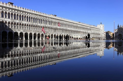 St Mark's Square, reflection of the Procuratie and the clock tower during the Acqua alta, Venice,