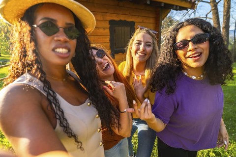 Four friends enjoying a sunny day in the countryside, capturing joyful moments together while