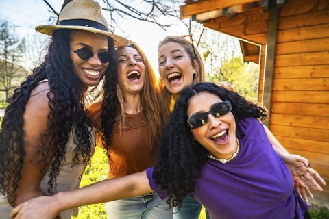 Four multi ethnic female friends are having fun together in a park, laughing and enjoying each