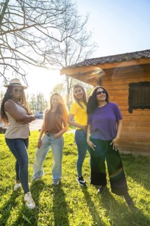 Four diverse female friends enjoying a sunny day together, posing confidently in front of a