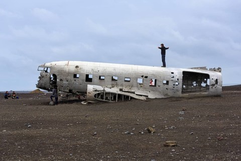 Tourist on aircraft wreckage, US Navy Douglas DC-3 transport plane, Sander, volcanic landscape,