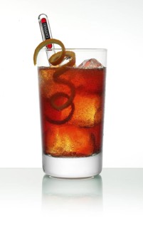 Campari cocktail in a long drink glass on ice with orange zest as garnish against a white