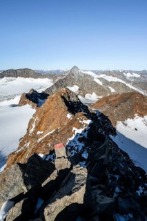 Narrow rocky ridge on the Wilder Freiger summit, picturesque high mountain landscape with snow,