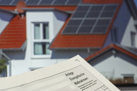 Close-up of tax return, energy measures attachment, in the background a picture of a solar roof on