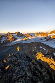 Mountaineers in front of a picturesque high mountain landscape at sunrise with alpenglow, glacier
