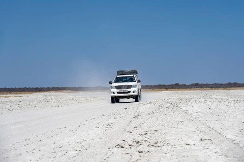 Off-road vehicle driving on a wide empty salt pan, Makgadikgadi Salt Pans, Botswana
