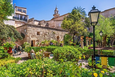 Lush green ornamental garden with visitors at the Arab Baths a historic site in city of Palma a
