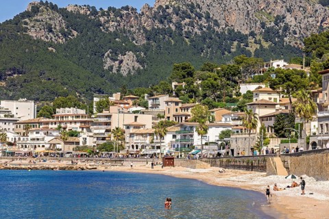 People sunbathing and bathing on the seashore at a idyllic coast village with houses at the