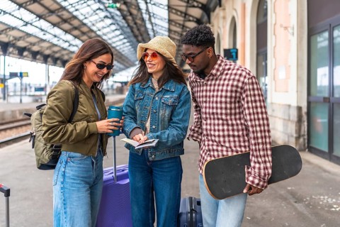 Happy tourists checking their train tickets and passports at the station, ready for their next