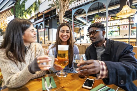 Happy multi ethnic friends toasting drinks at a brewery, enjoying each other's company and