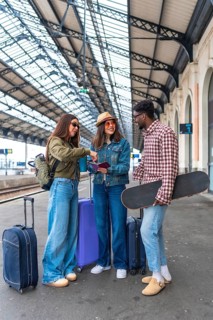 Group of friends waiting at the railway station, displaying passports and tickets while eagerly